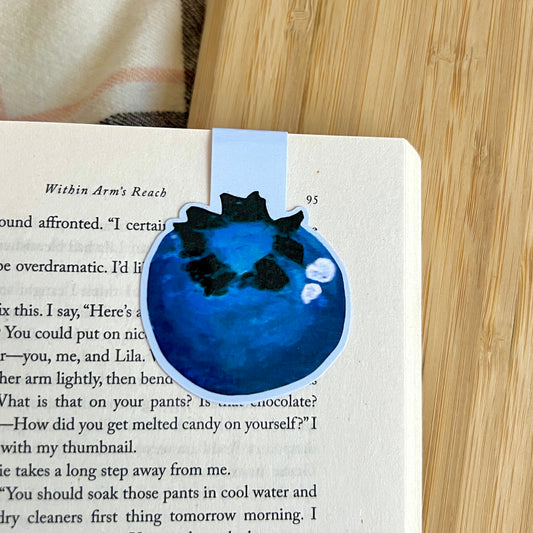 blueberry bookmark marking page in book on wooden surface