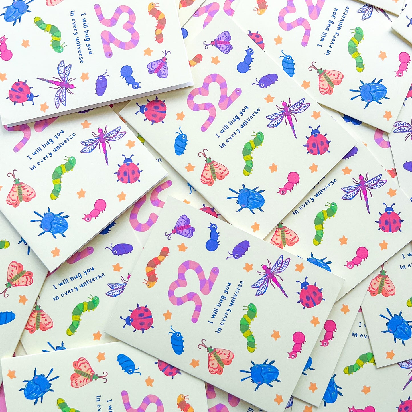 stack of greeting cards with an illustration of various bugs and text 'I will bug you in every universe' on white background