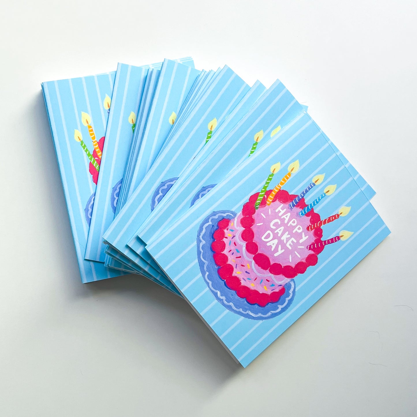 stack of birthday cards with cake illustration and text 'happy cake day' against a white background