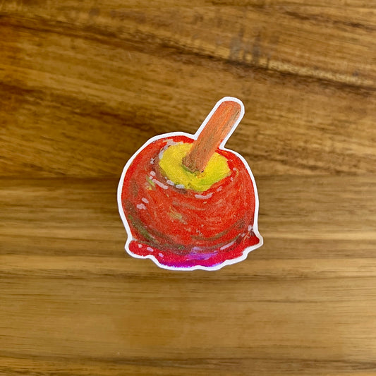 Sticker of a red candy apple on a wooden surface