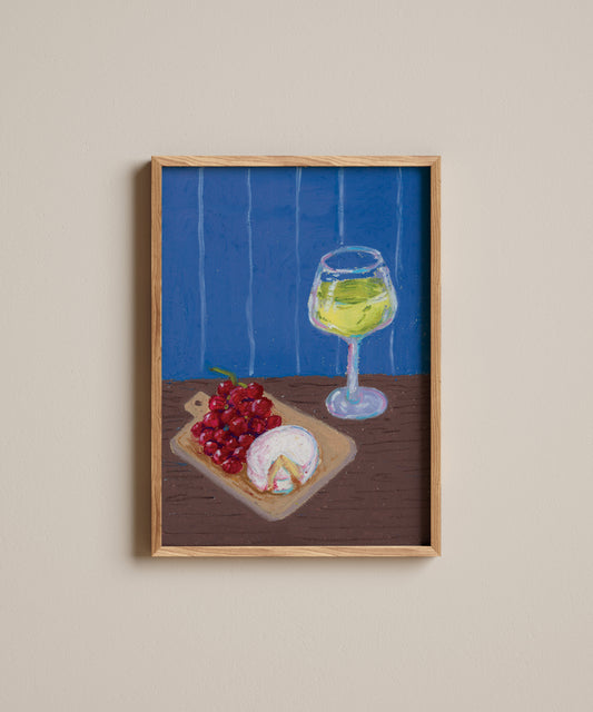 Framed artwork of a glass of white wine, grapes, and a piece of cheese on a wooden table with a blue background.
