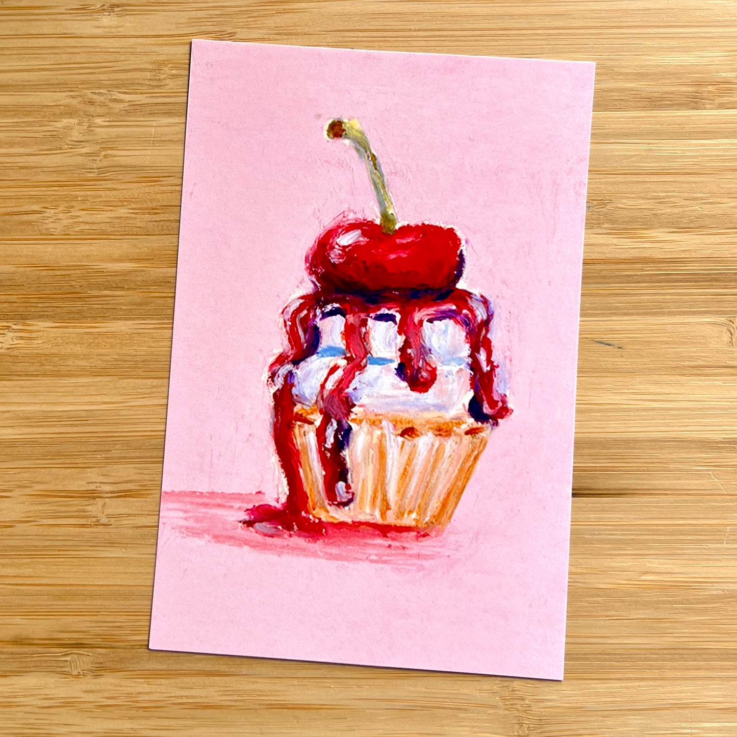 cupcake with a cherry on top and dripping sauce on a pink background