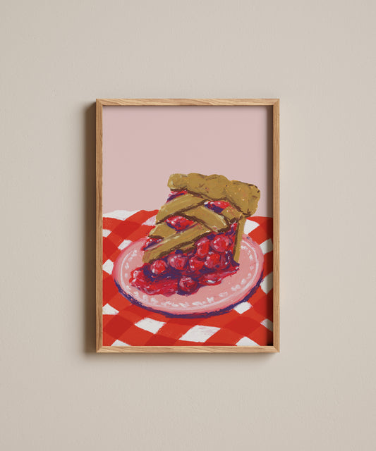 Framed artwork of a slice of pie on a red and white checkered tablecloth.