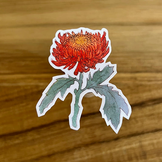 Sticker of a red flower with green leaves on a wooden surface