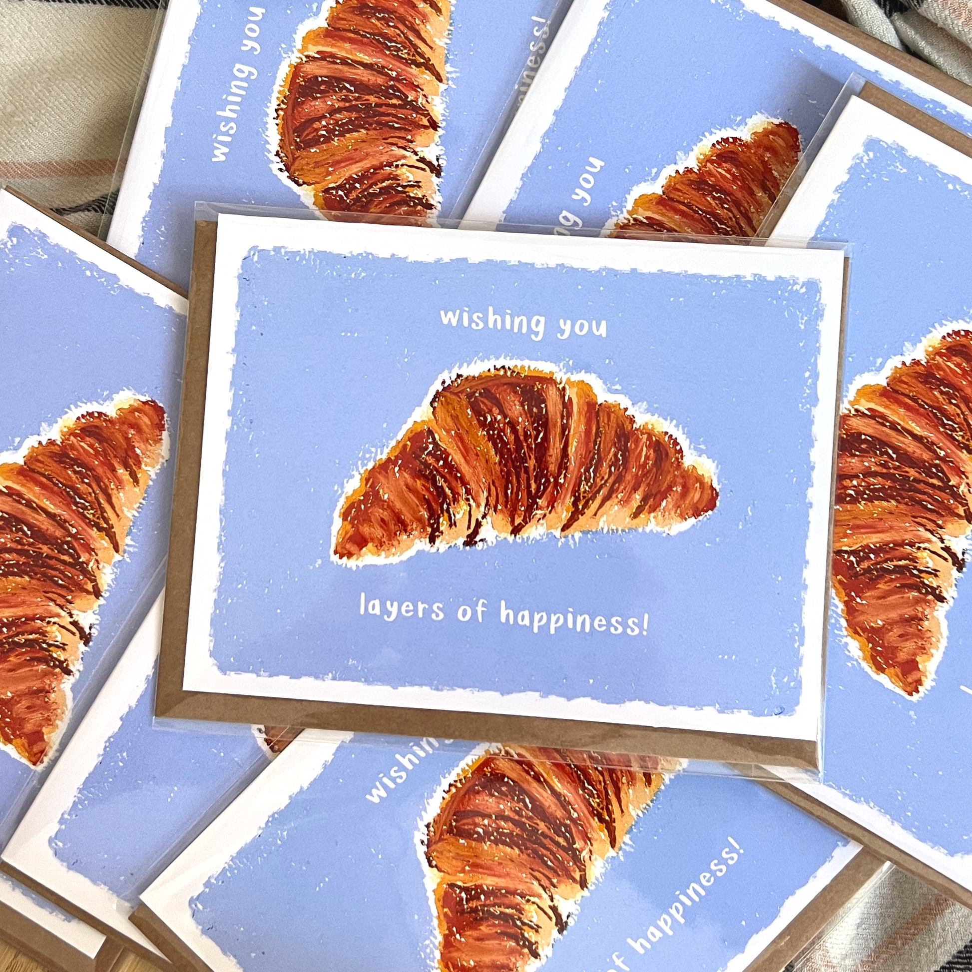 Greeting cards with croissant illustration and text on blue background
