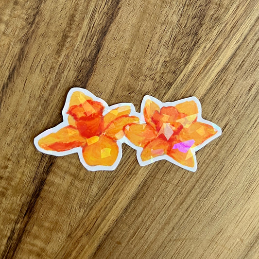 Two orange floral stickers on a wooden surface