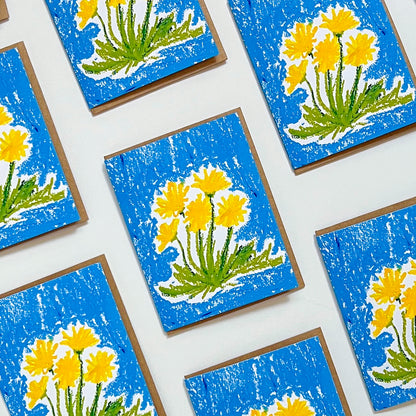 Greeting cards with yellow flower designs on blue backgrounds, arranged on a white surface.