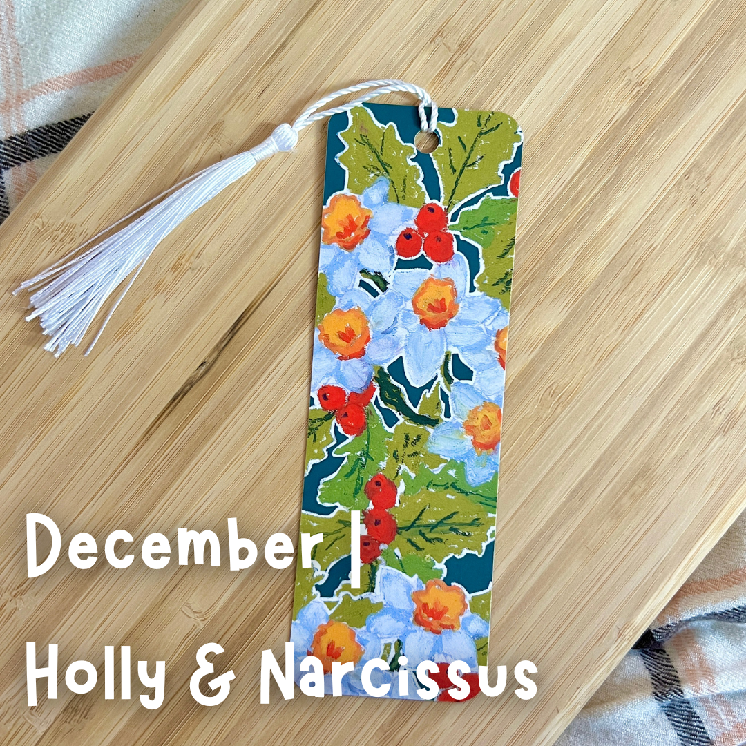 Floral bookmark with tassel on a wooden surface, featuring 'December' and 'Holly & Narcissus'.