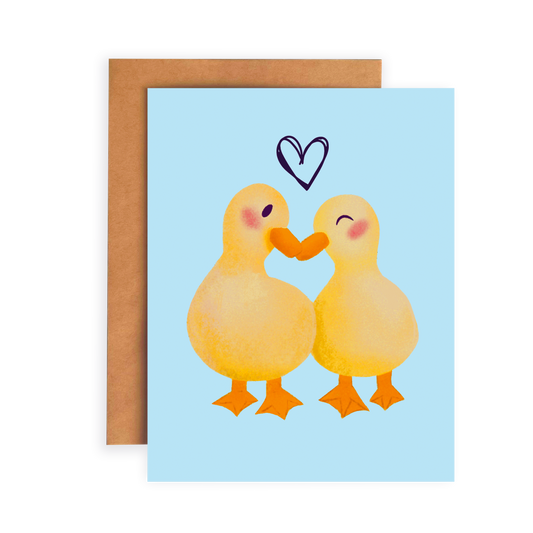 Greeting card with two ducks embracing and a heart above them on a light blue background.