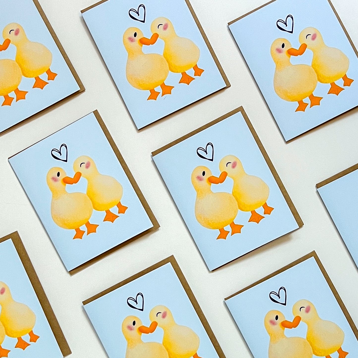 Set of greeting cards with cartoon ducks holding hands on a light blue background.