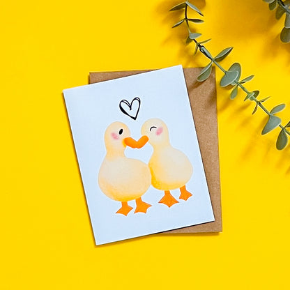 Card with two ducks and a heart on a yellow background