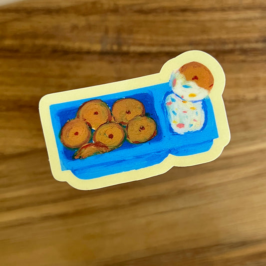 Sticker of a blue tray with cookies and a cake icing on a wooden surface