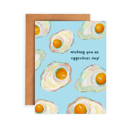 Greeting card with fried egg illustrations and text 'Wishing you an eggcellent day!' on a blue background.