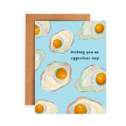 Greeting card with fried egg illustrations and text 'Wishing you an eggcellent day!' on a blue background.