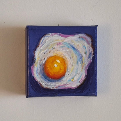 fried egg painting on purple background hung on white wall