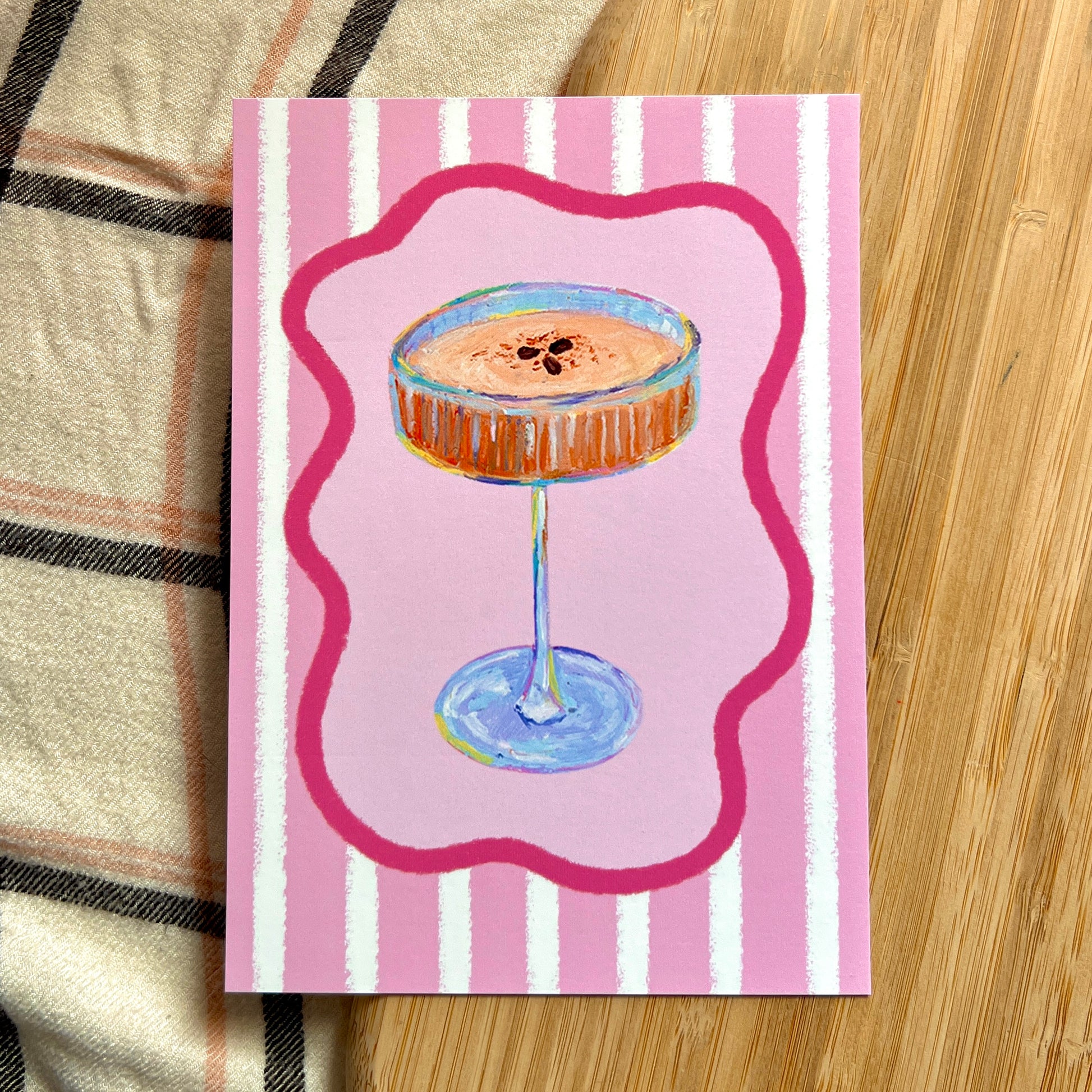 illustrated espresso martini with pink striped background on wooden and plaid surface