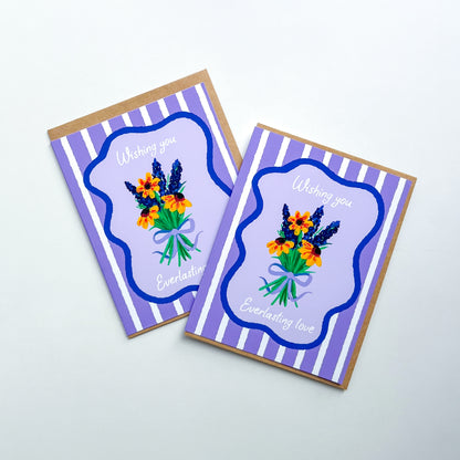 two wedding cards with hand drawn flowers and text 'wishing you everlasting love' on a purple striped background with Kraft envelope against white background