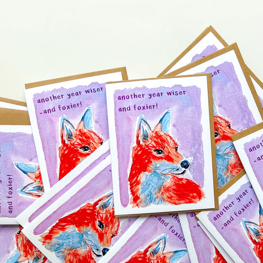 Stack of greeting cards with fox illustration and text on a white background