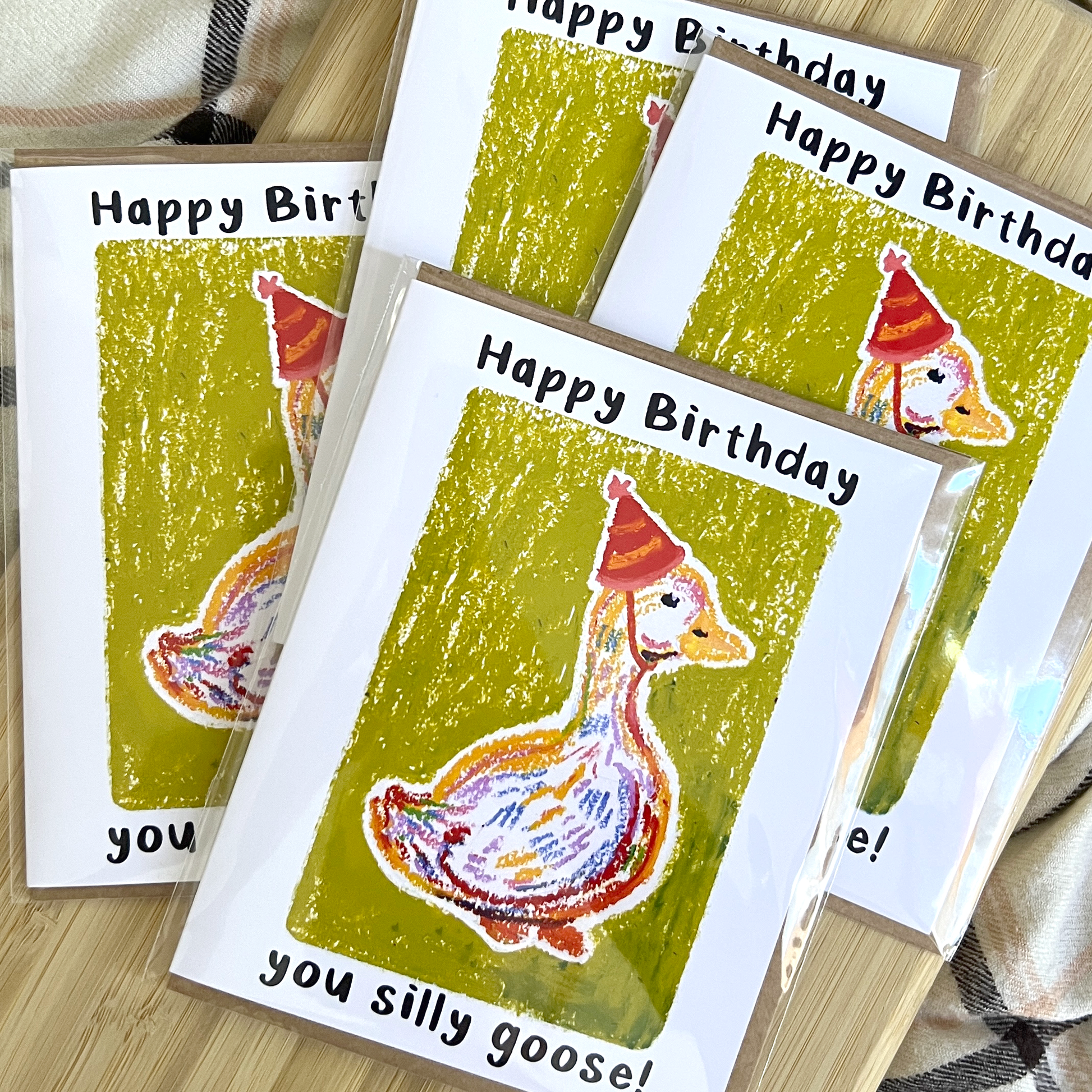 Set of birthday cards with a goose illustration and 'Happy Birthday You Silly Goose!' text on a wooden surface.