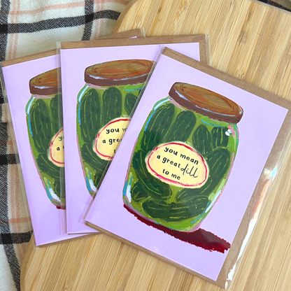 Three greeting cards with pickle jar illustrations on a wooden surface.