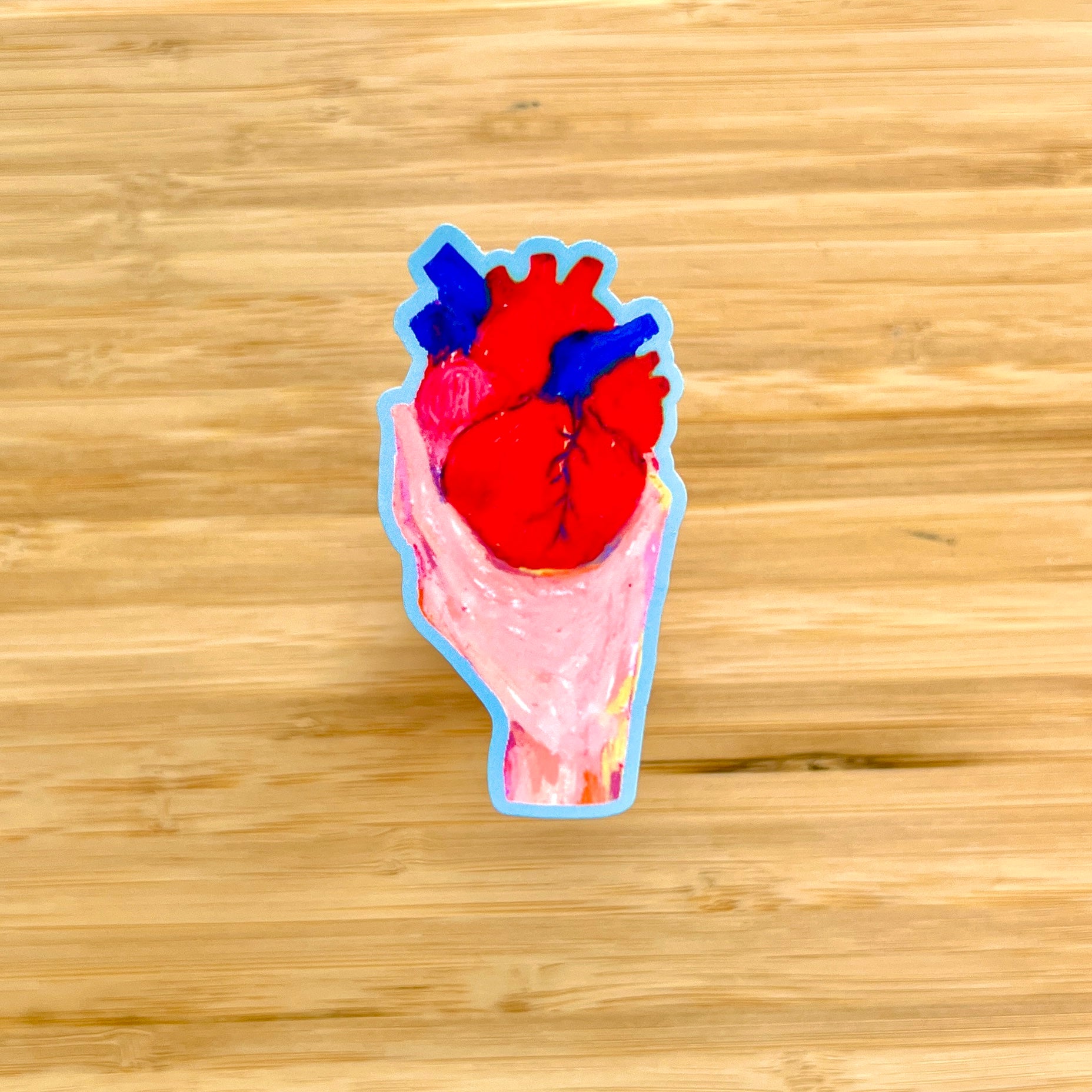Sticker of a hand holding human heart on a wooden surface