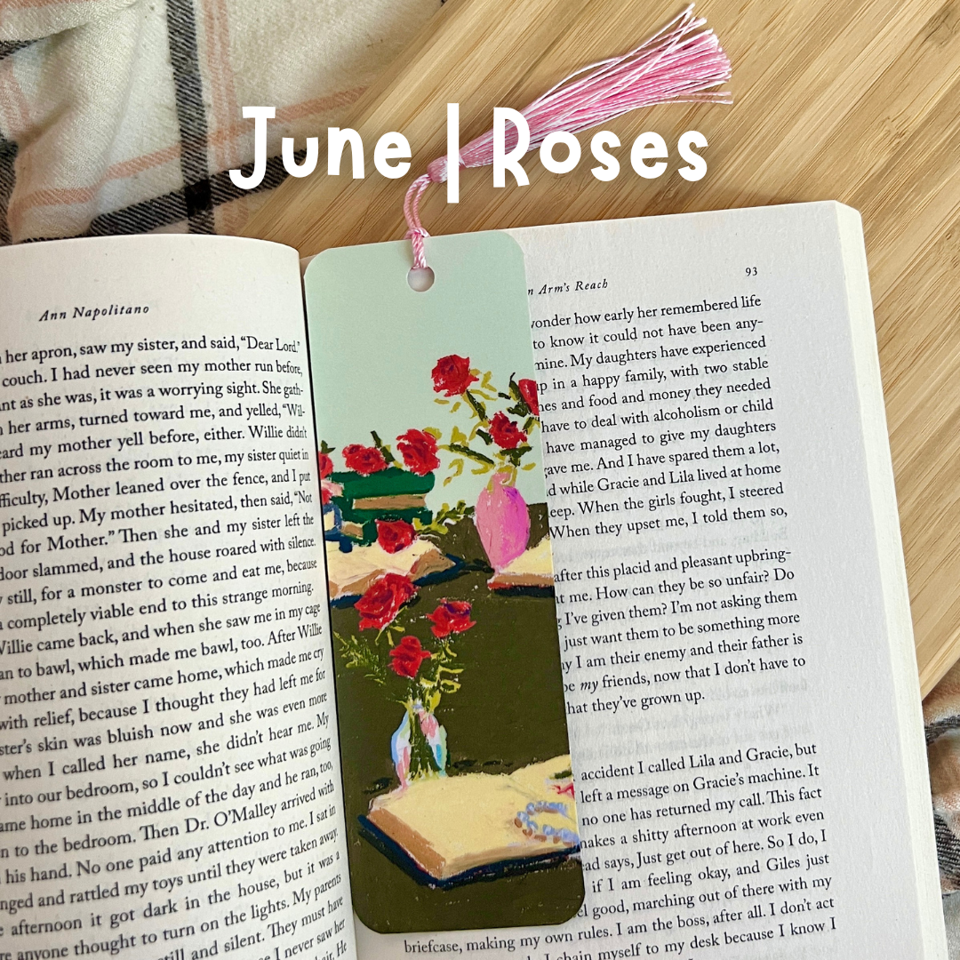 Book with a floral bookmark on a wooden surface, with text 'June Roses'.