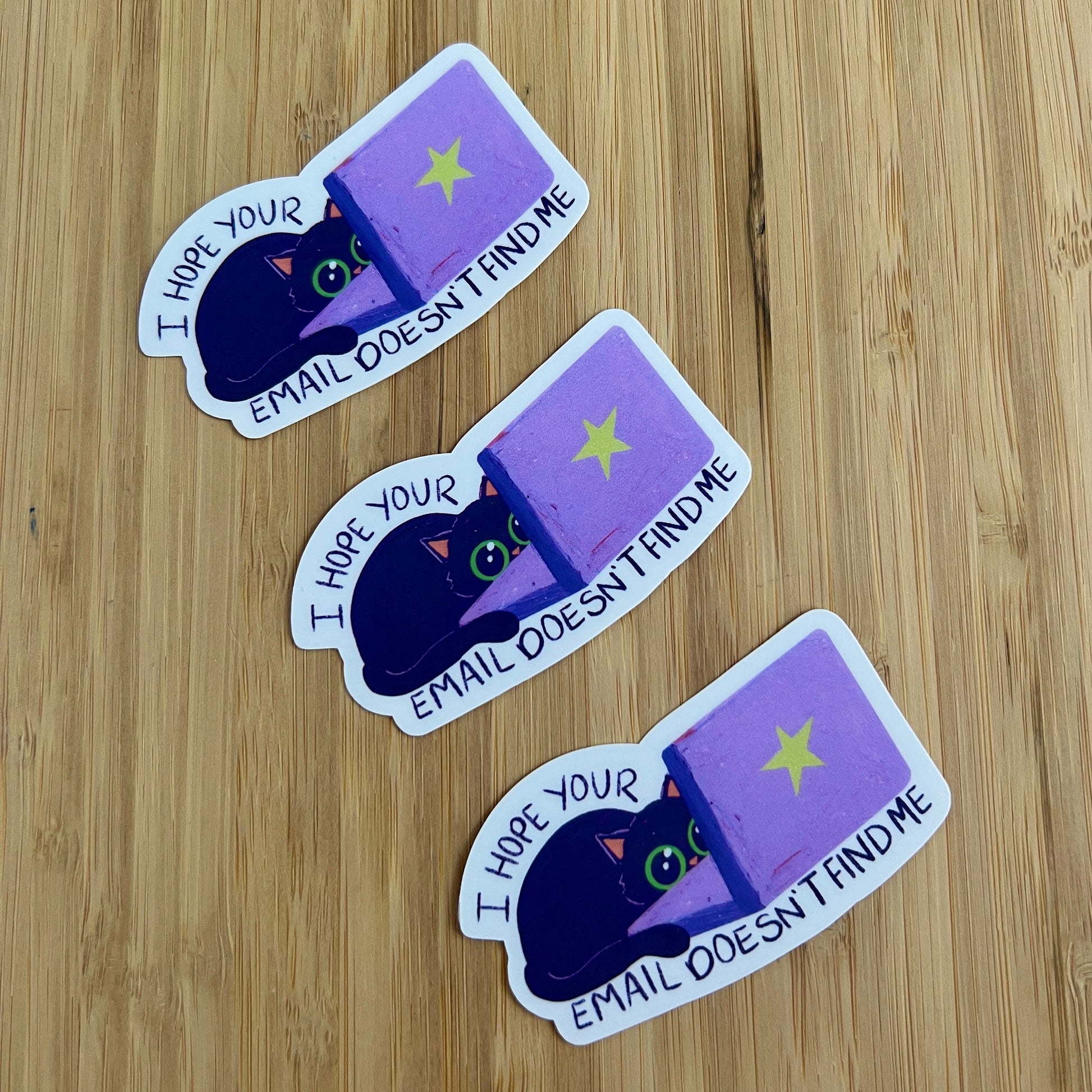 three stickers of cat behind laptop with text 'I hope your email doesn't find me'