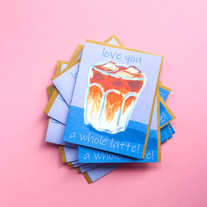 Stack of greeting cards with a coffee cup illustration and text 'love you a whole latte' on a pink background