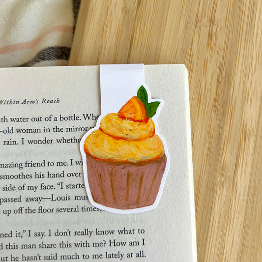 Cupcake-shaped bookmark on a book with a wooden surface in the background