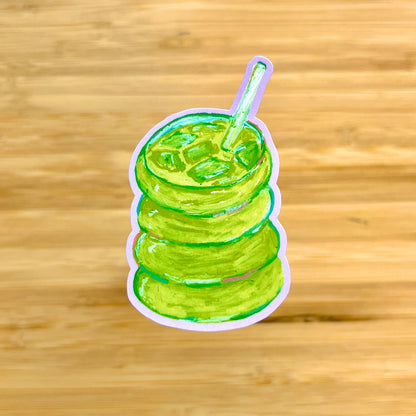 Sticker of a green matcha with a straw on a wooden background