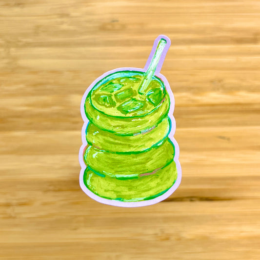 Sticker of a green matcha with a straw on a wooden background