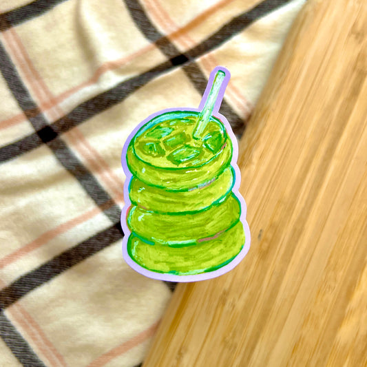 Illustration of a green matcha with a straw on a plaid fabric background