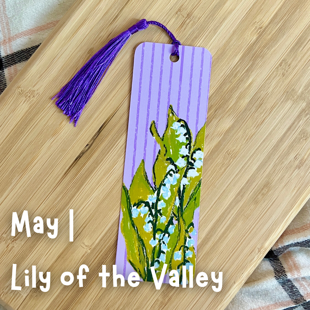Bookmark with floral design and purple tassel on a wooden surface