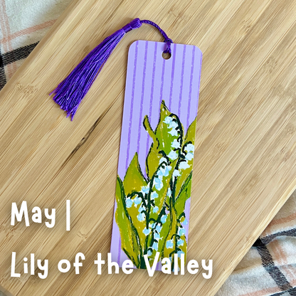 Bookmark with floral design and purple tassel on a wooden surface
