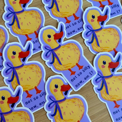 Stickers of a yellow duck with a purple bow on a wooden surface