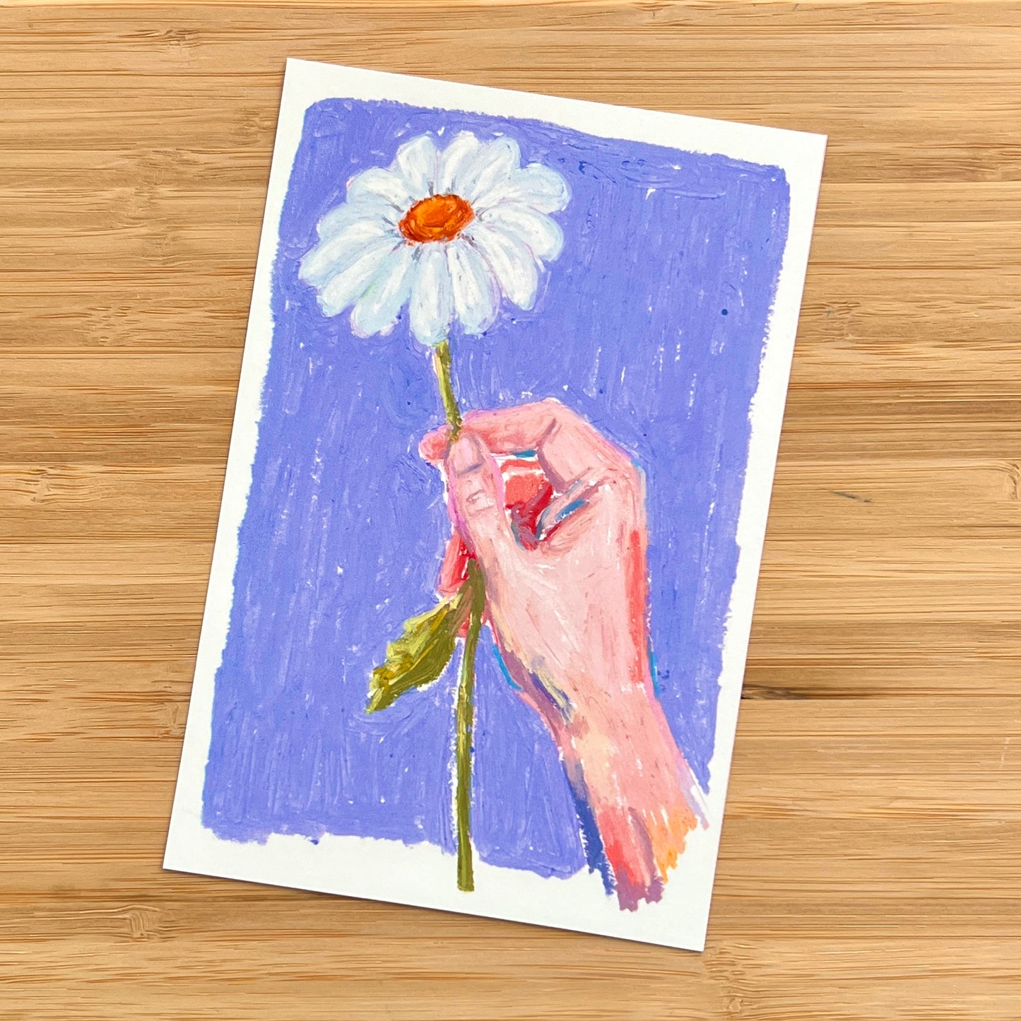 oil pastel drawing of a hand holding a daisy on blue background