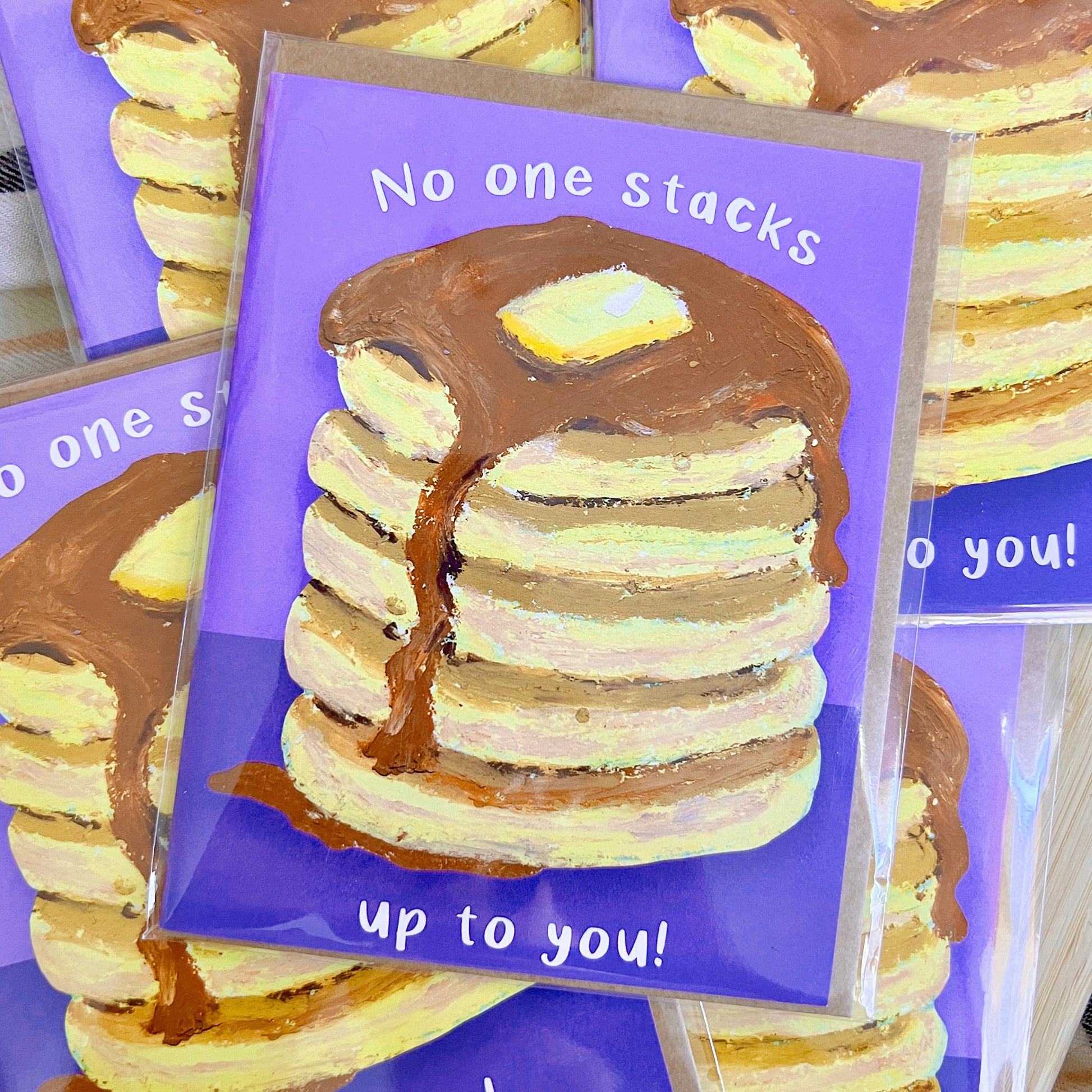 Stack of cookies with a purple card saying 'No one stacks up to you!' on a wooden surface.
