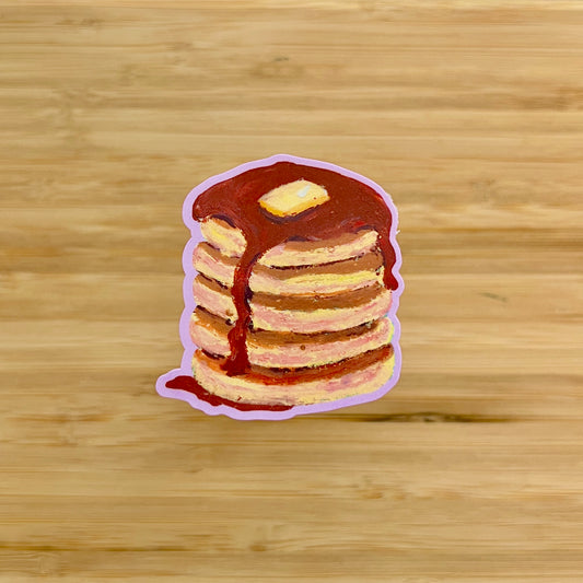 Stack of pancakes with syrup and a piece of butter on a wooden background