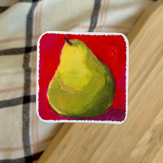Painting of a green pear on a red background, placed on a wooden surface with a plaid fabric.