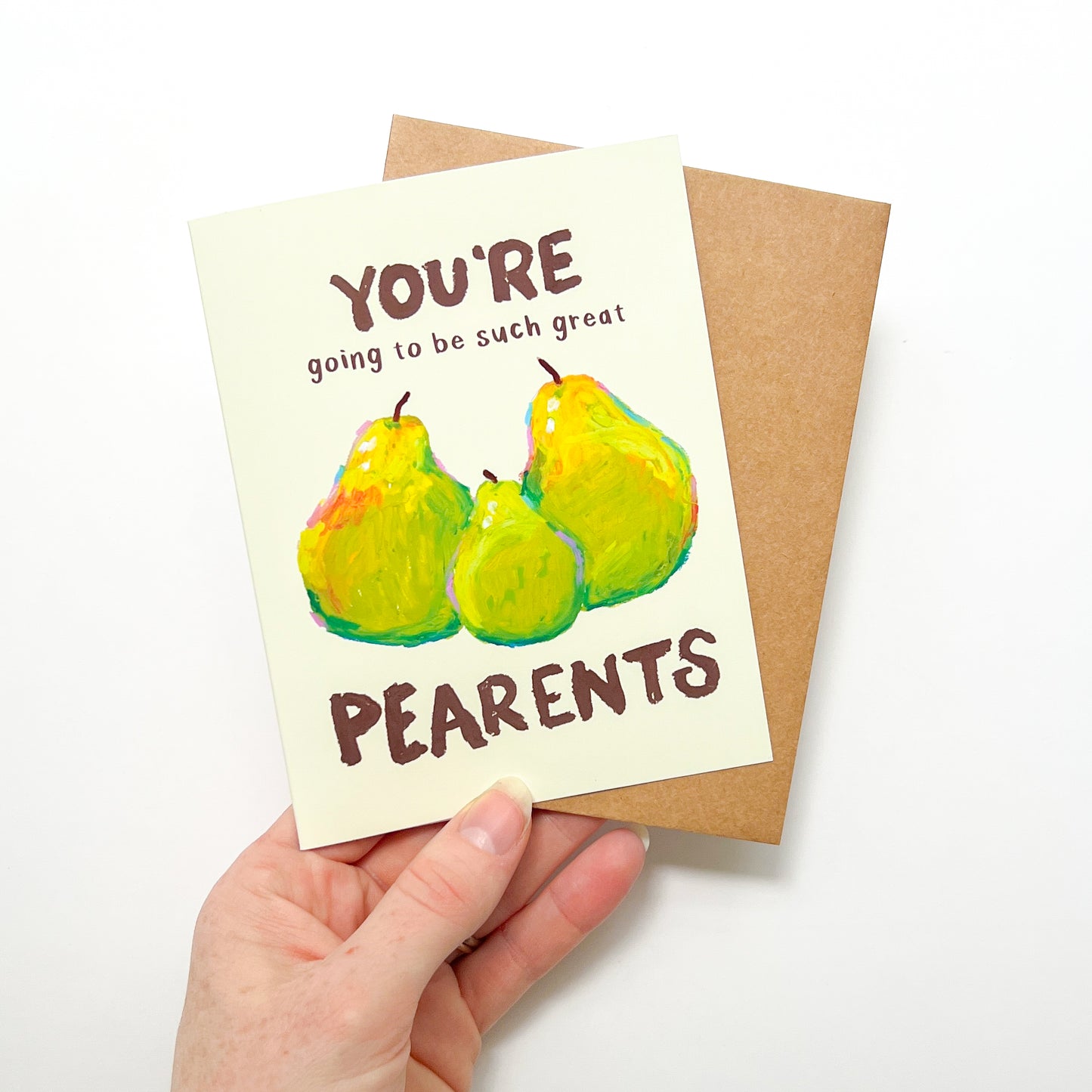 Greeting card with pears and text held by a hand on a white background