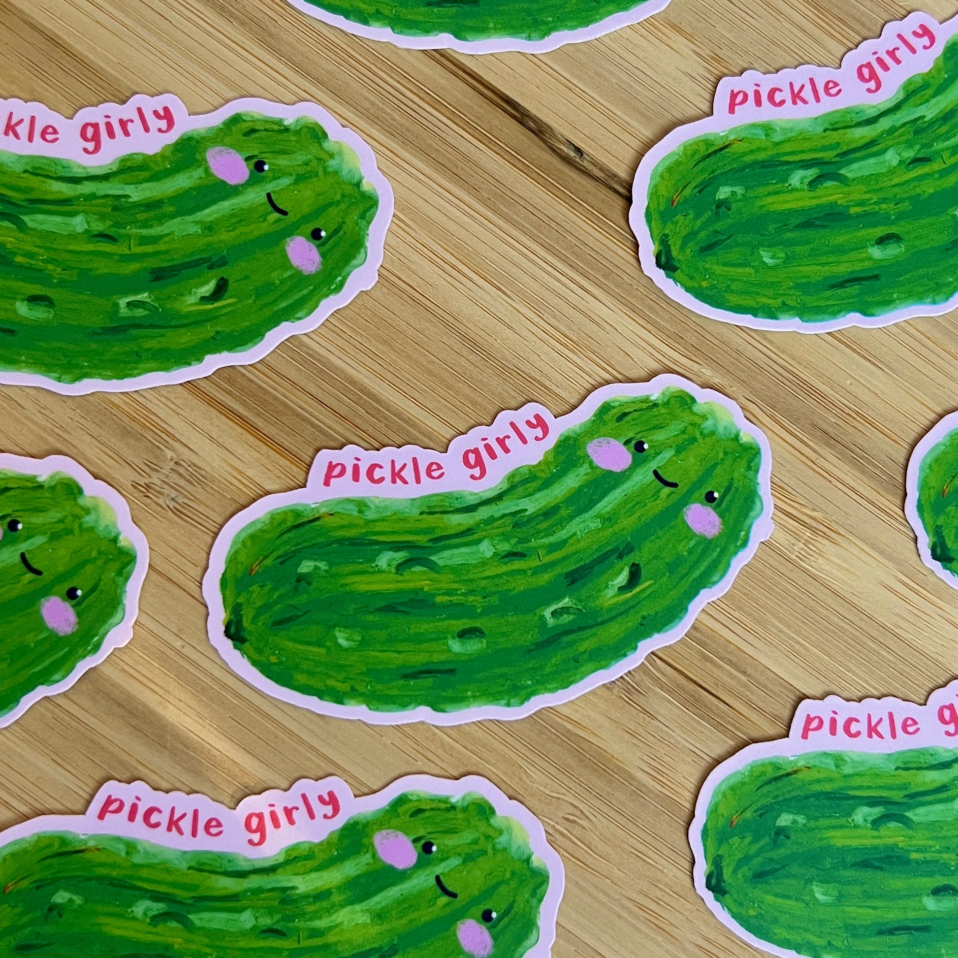 Green pickle-shaped stickers with 'pickle girly' text on a wooden surface