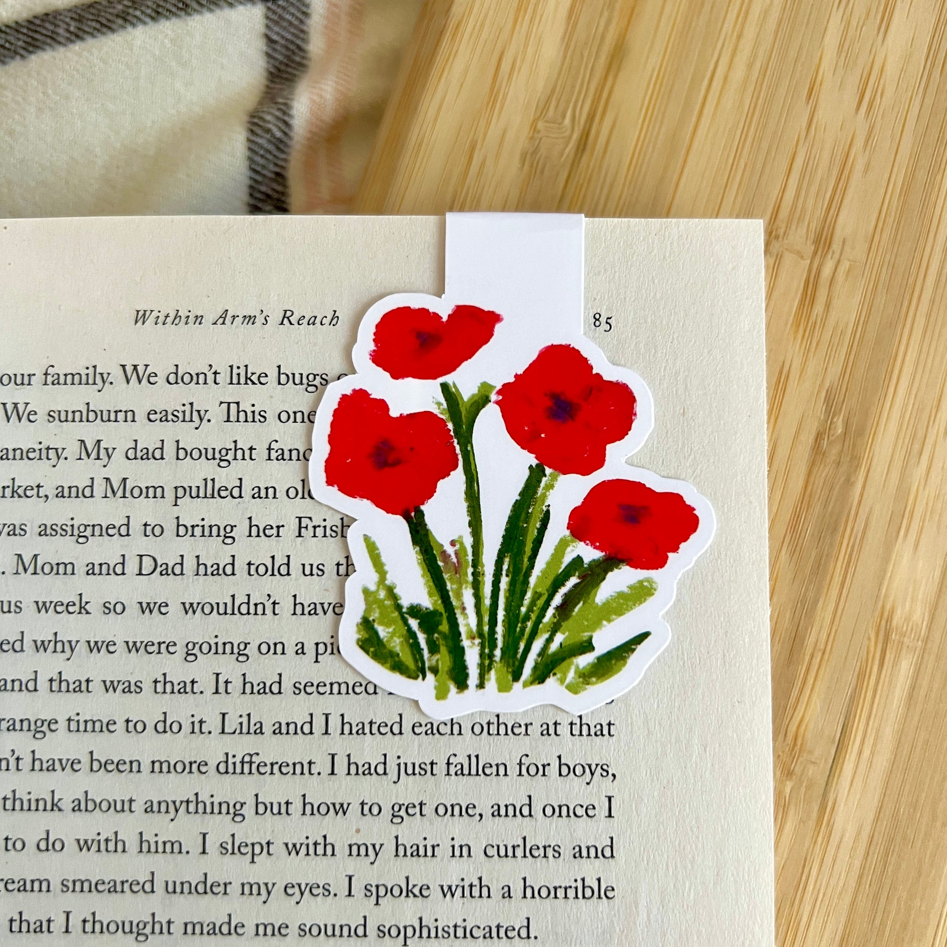 Sticker of red flowers on a book page with a wooden surface in the background