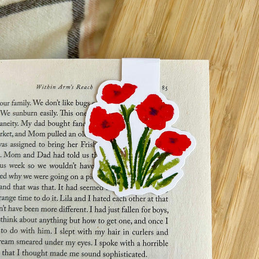Sticker of red flowers on a book page with a wooden surface in the background