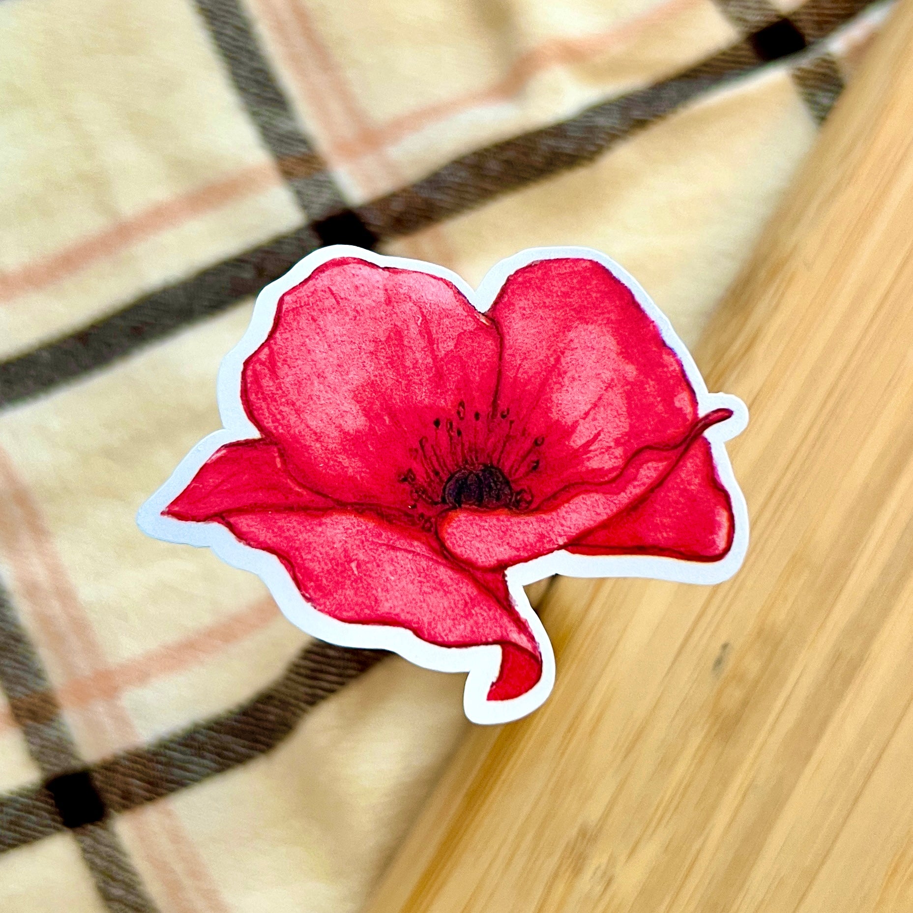 Red flower-shaped sticker on a checkered fabric background