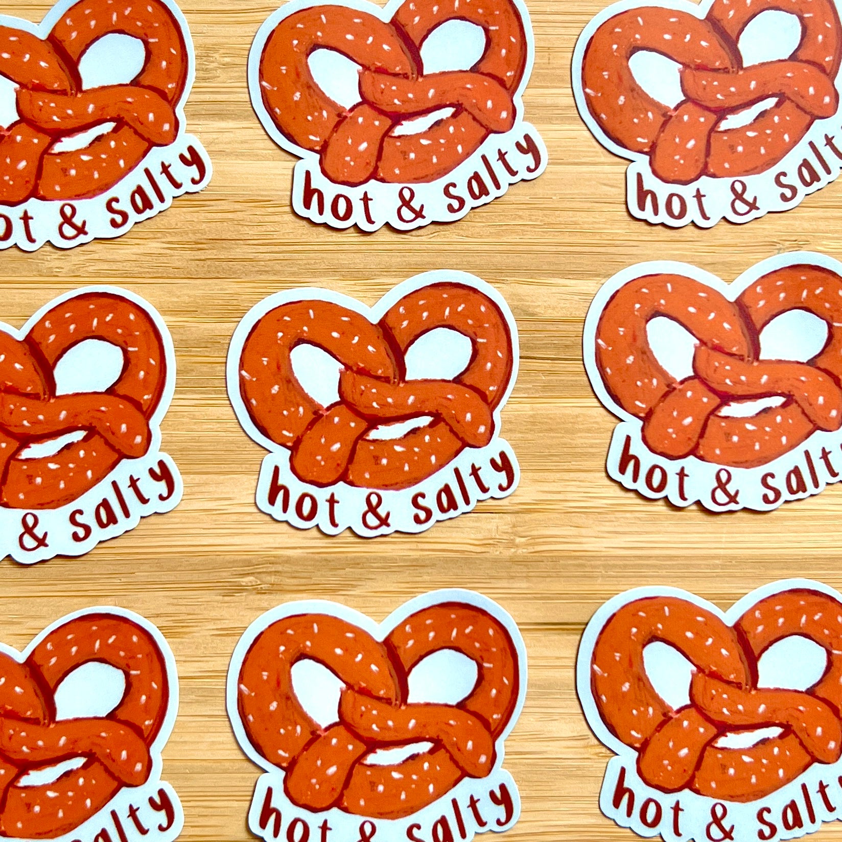 Stickers of pretzels with 'hot & Salty' text on a wooden surface