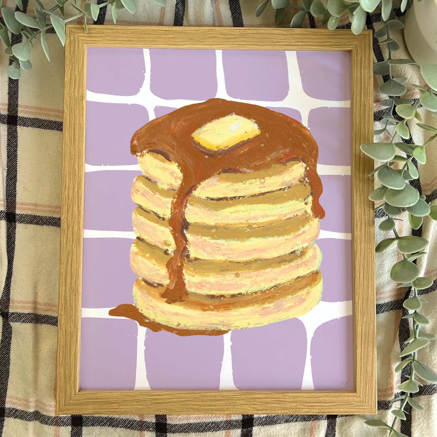 Framed artwork of pancakes with syrup on a purple checkered background