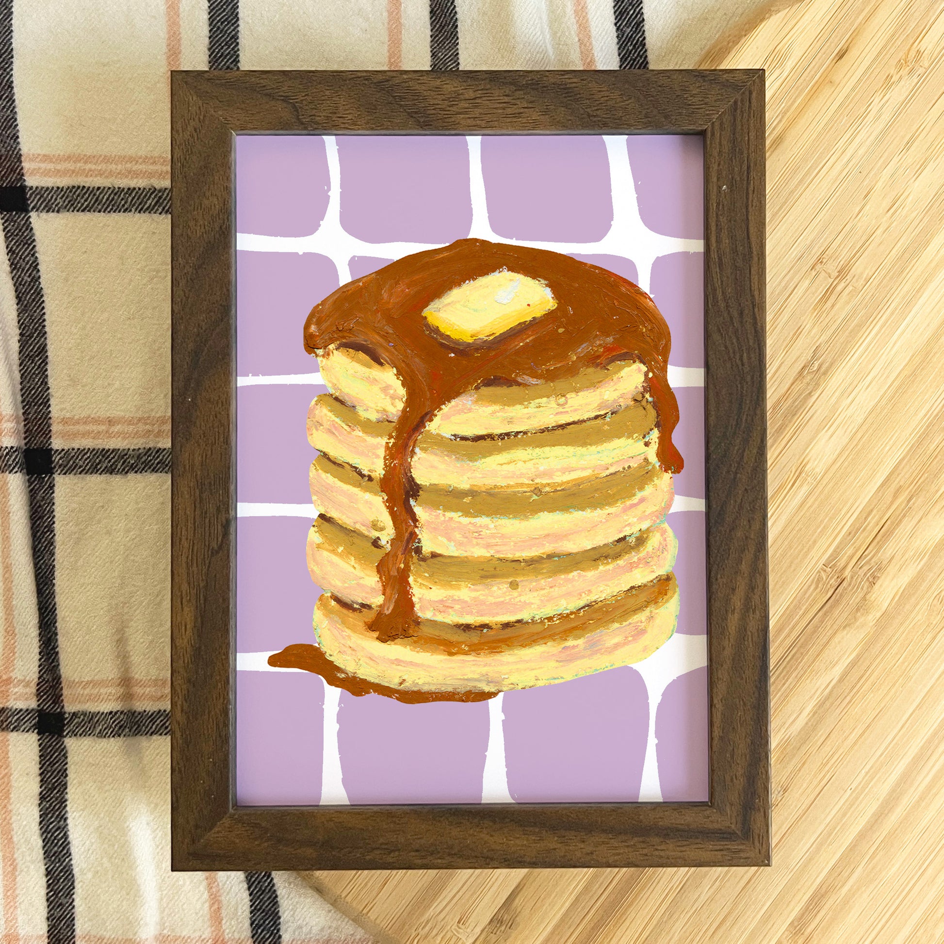 Framed artwork of a stack of pancakes with syrup on a purple background