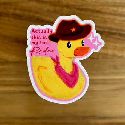 Sticker of a duck wearing a cowboy hat and bandana with text on a wooden surface