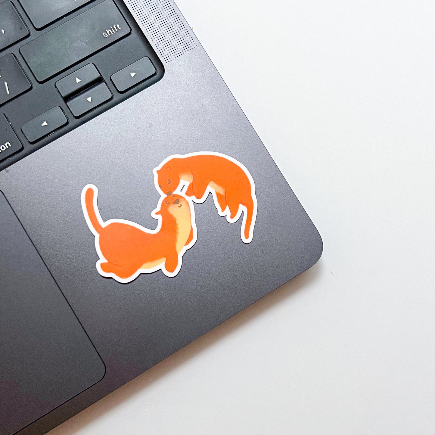 Two orange otters stickers on a laptop keyboard