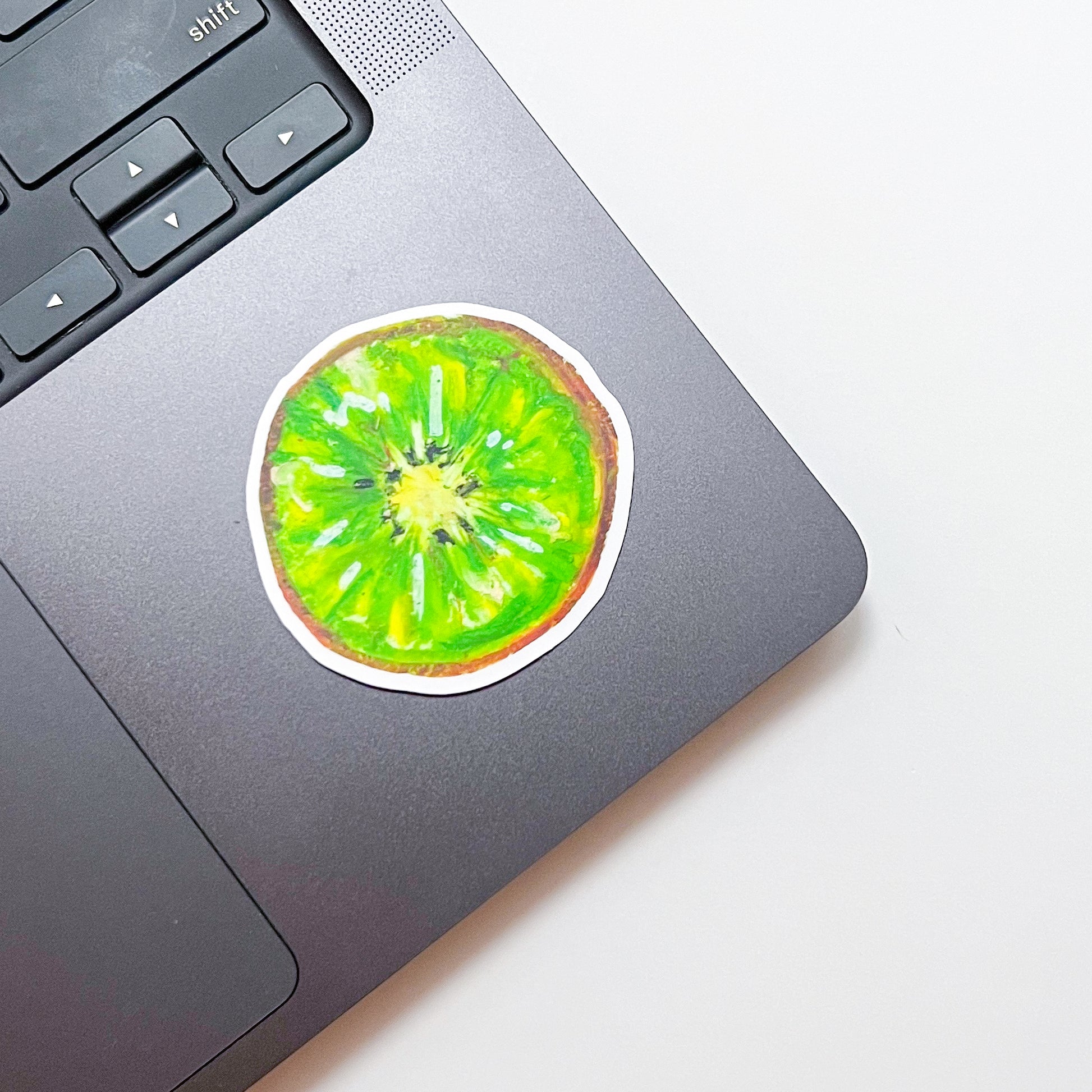 Laptop with a kiwi fruit sticker on a white surface
